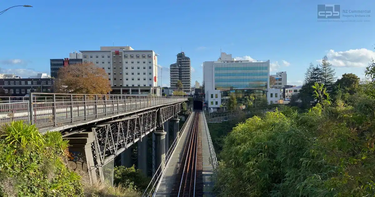 Urban view of Hamilton’s commercial buildings and railway bridge under clear blue sky.